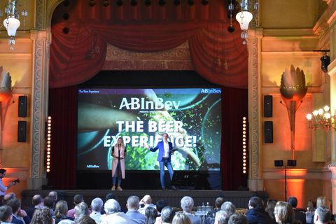 Deux présentateurs sur scène devant l'écran « The Beer Experience » d'AB InBev