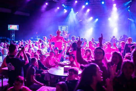Une foule attablée sous les projecteurs, bras levés, pendant le quiz du 15 août à Malèves